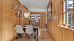 A wooden interior with a dining area featuring a table and chairs, a hanging light fixture, and a window with a view. - Awesome home in Højby with WiFi (Højby)