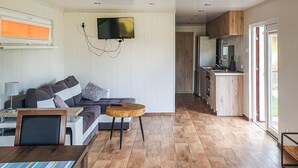 A modern living room with a sofa, a coffee table, and a TV mounted on the wall. - Cozy home in Biskupiec with lake view (Biskupiec)