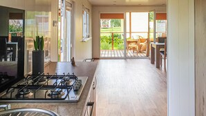 A kitchen with a gas stove, a sink, and a dining area with chairs and a table. - Cozy home in Biskupiec with lake view (Biskupiec)