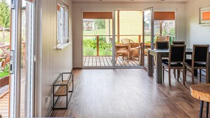 A spacious patio with a wooden deck, a dining area with wicker chairs, and a sliding glass door leading to a garden. - Cozy home in Biskupiec with lake view (Biskupiec)
