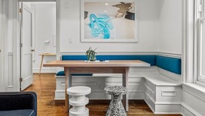 A modern dining area with a wooden table, blue cushioned bench, and a unique abstract painting on the wall. - Luxury in Ritt Sq. | Parking | Hosted By StayRafa (Philadelphia)