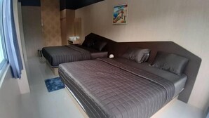 Ein modernes Schlafzimmer mit einem großen Bett, einem kleineren Bett und einer Schlafcouch.