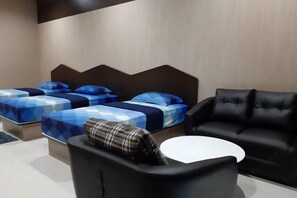 A modern hotel room with two beds, a black leather sofa, and a small white table. - Tho Mai Resort by Zuzu (Khlong Yai)