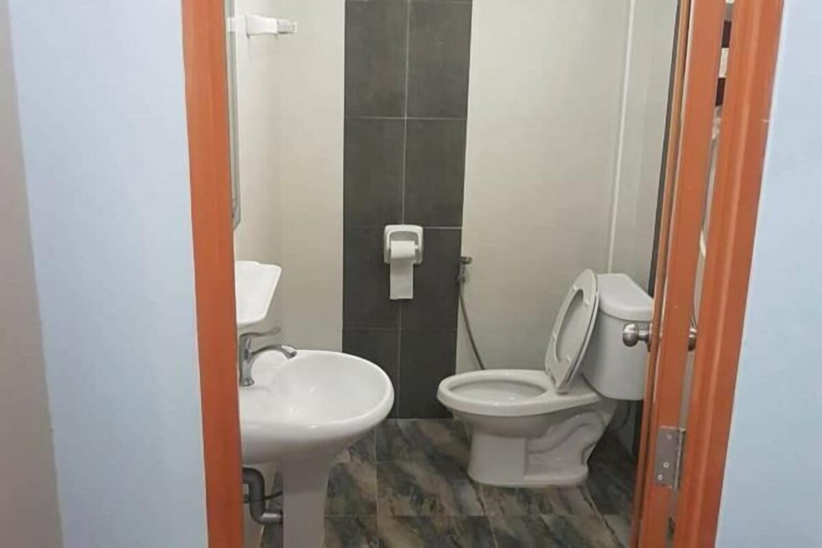 A small bathroom with a toilet, sink, and a towel dispenser.
