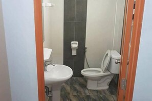 A small bathroom with a toilet, sink, and a towel dispenser. - Tho Mai Resort by Zuzu (Khlong Yai)