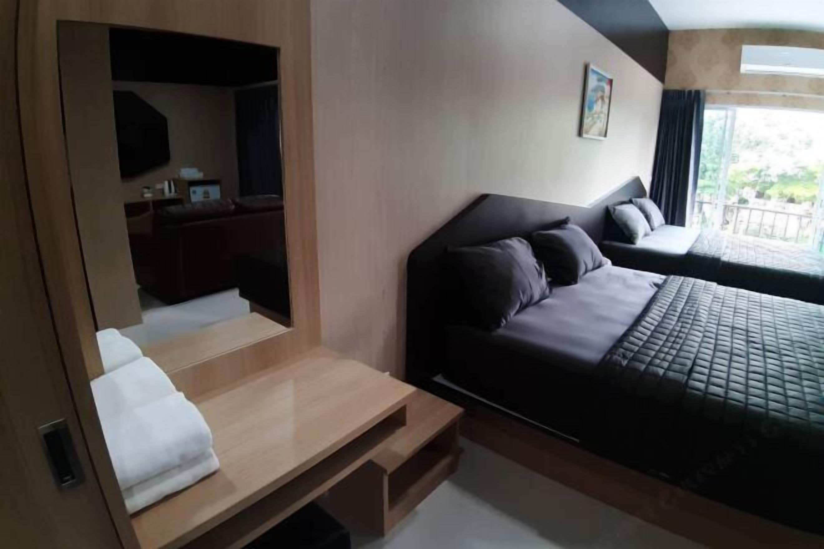 A modern hotel room with a bed, a desk, and a view of the outdoors.