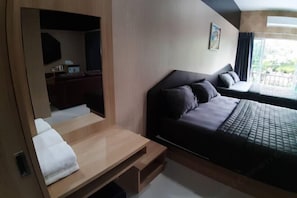 A modern hotel room with a bed, a desk, and a view of the outdoors. - Tho Mai Resort by Zuzu (Khlong Yai)