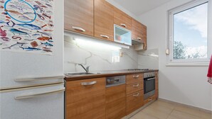 A modern kitchen with wooden cabinets, a built-in oven, and a window providing natural light. - 1 bedroom gorgeous apartment in Zadar (Zadar)