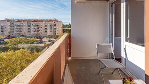 A balcony with a chair and a table, overlooking a parking area and residential buildings. - 1 bedroom gorgeous apartment in Zadar (Zadar)