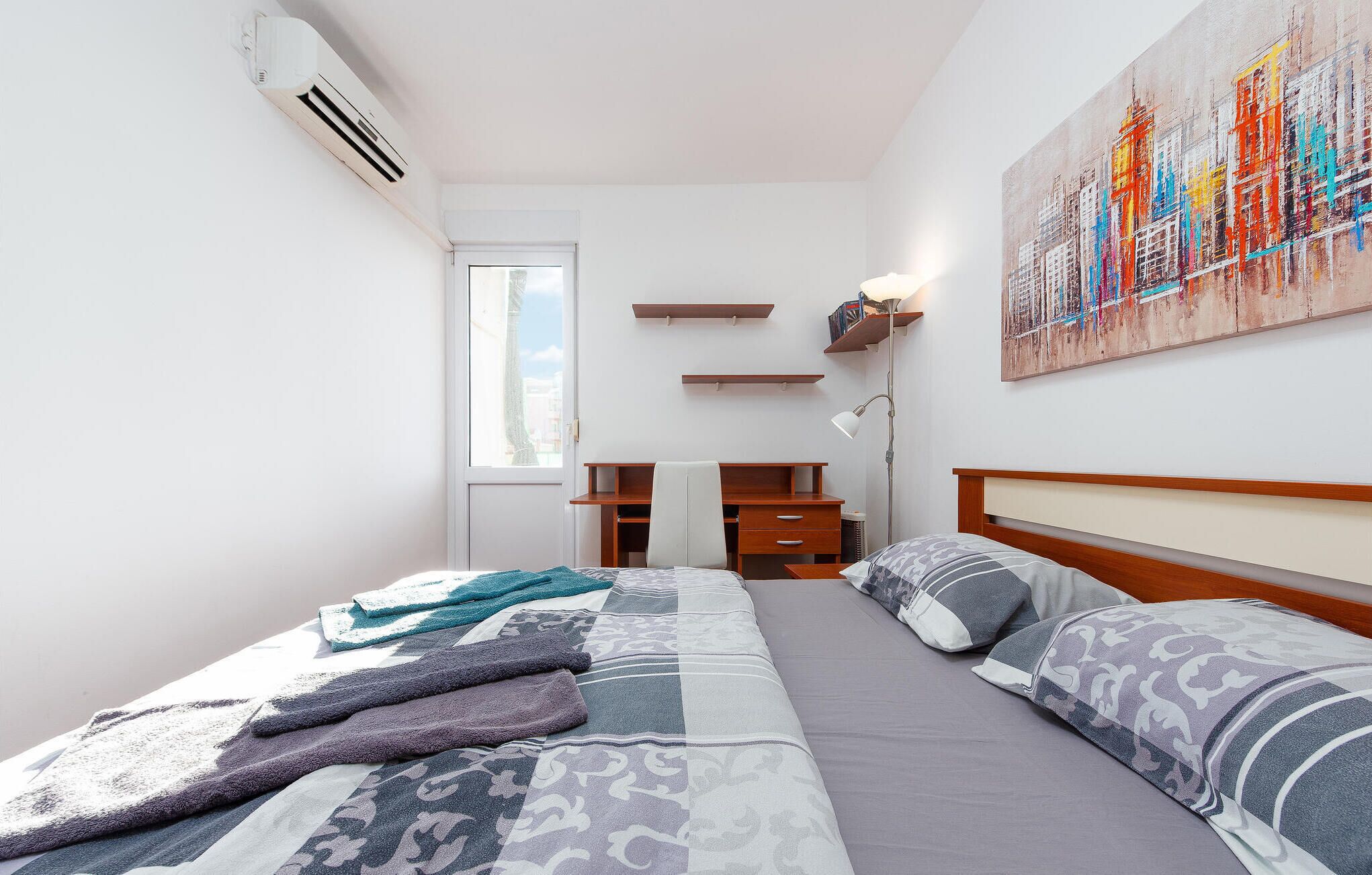 A bedroom with a bed, bedside tables, a desk, and a chair.