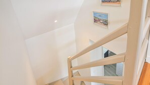 Una escalera blanca con barandilla de madera que conduce a una plataforma.