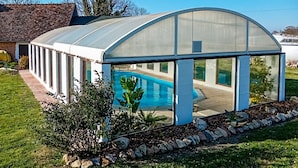 A greenhouse structure with a transparent roof, a swimming pool, and a garden area with rocks and plants. - Stunning home in Grandmesnil (Grandmesnil)