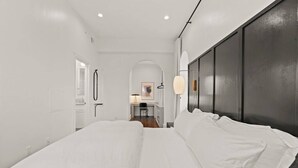 Une chambre d’hôtel moderne avec un grand lit, un mur d’accent de couleur sombre et un petit espace bureau avec une chaise.