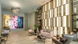 Un hall d’entrée moderne doté d’un espace salon, d’un grand mur orné de panneaux verticaux et d’un lustre.