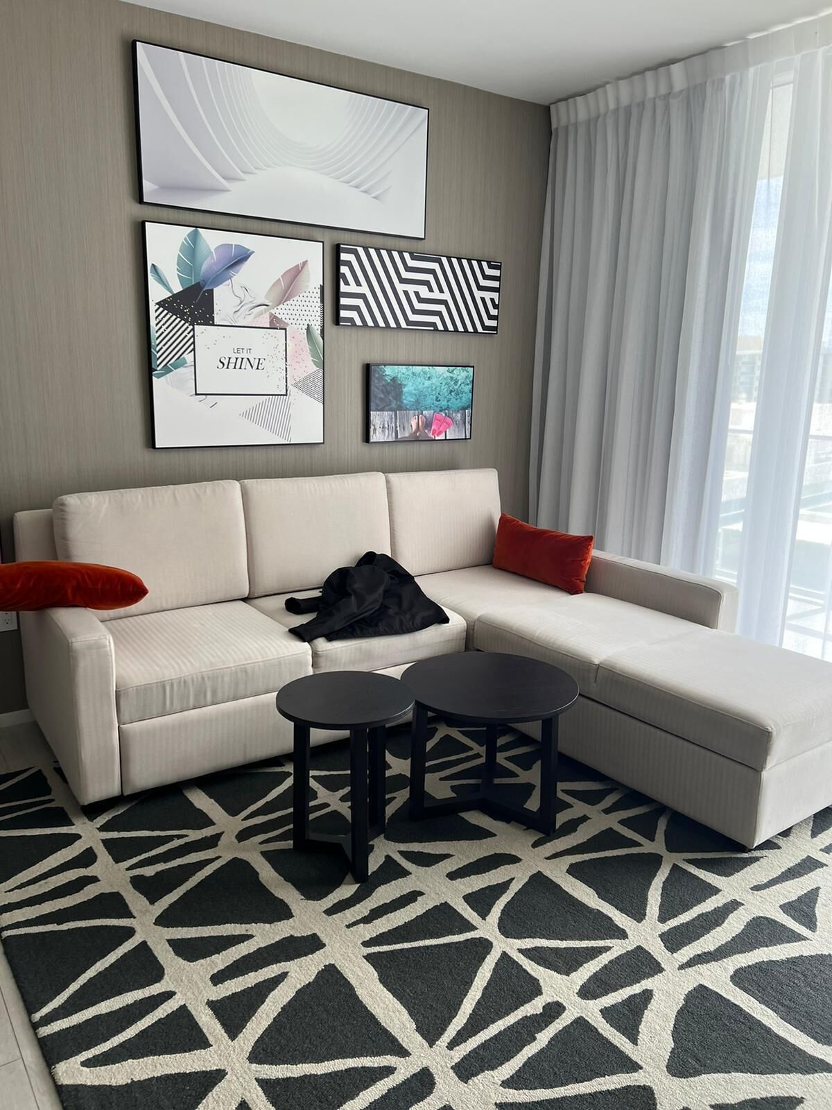 A modern living room with a sectional sofa, two round coffee tables, and abstract wall art.