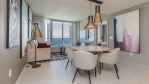 Un salon moderne avec une table de salle à manger ronde, deux chaises, un canapé et une grande fenêtre.