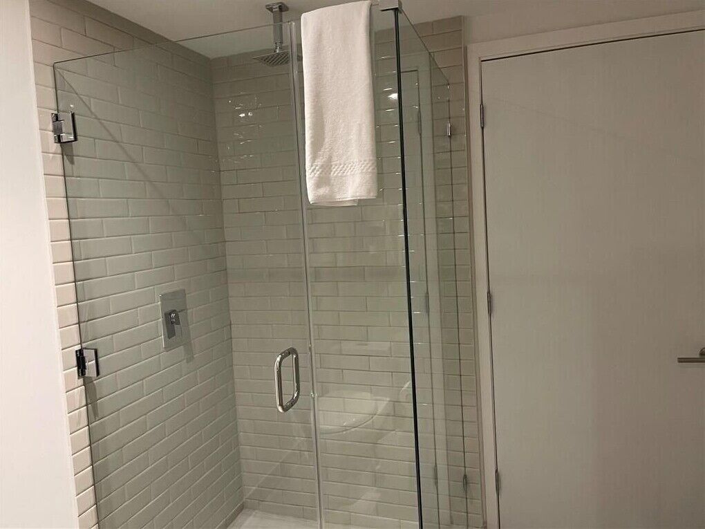 A glass-enclosed shower with a white towel hanging on the door.