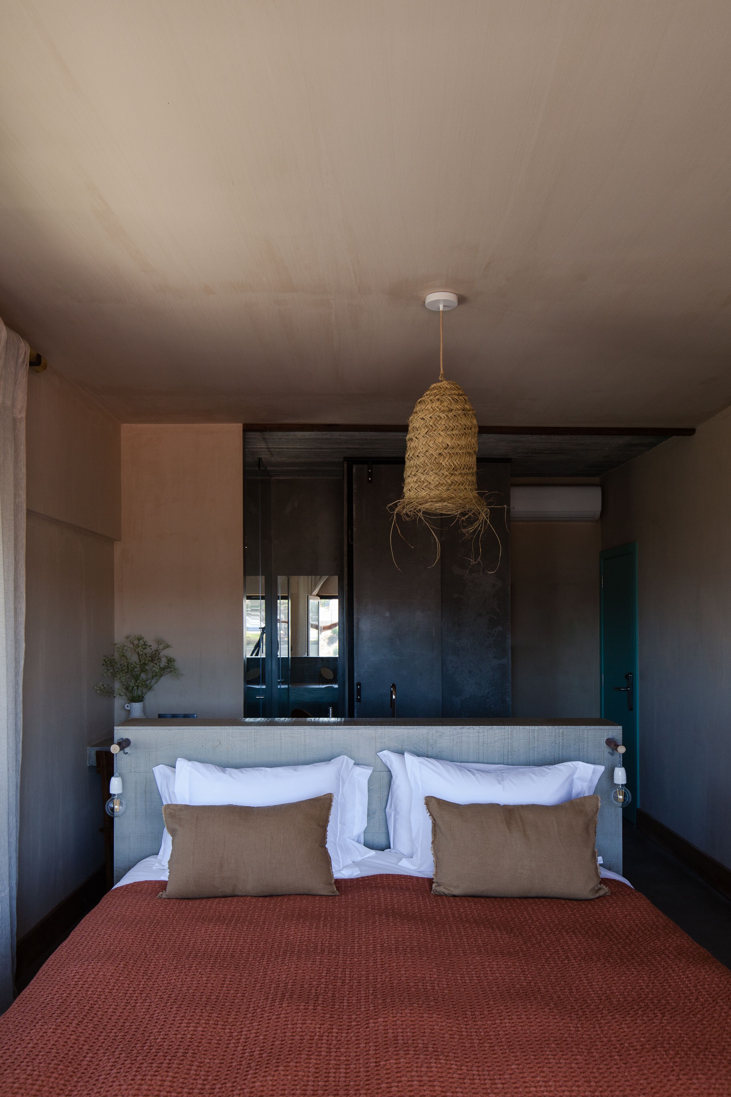 Un dormitorio con una cama grande, una lámpara colgante, una ventana y una puerta.