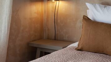 Una habitación con una cama, una mesita de noche y una lámpara de pared.