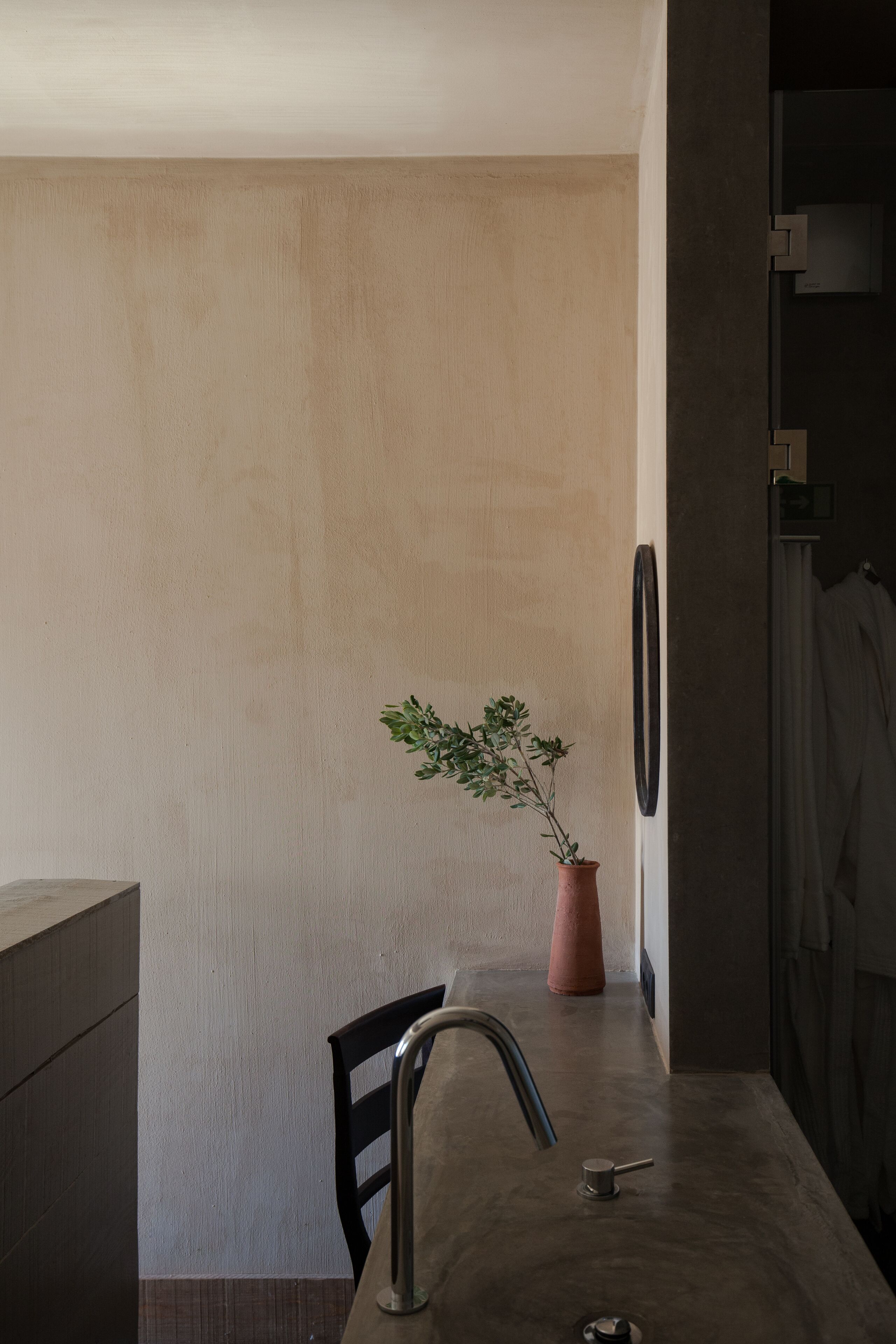 Une salle de bain moderne au design minimaliste, avec un grand miroir, une plante en pot et un robinet élégant.