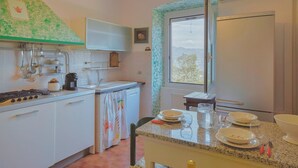 A kitchen with white cabinets, a stove, a sink, and a window with a view of the outdoors. - Nice apartment in Camogli with WiFi (Camogli)
