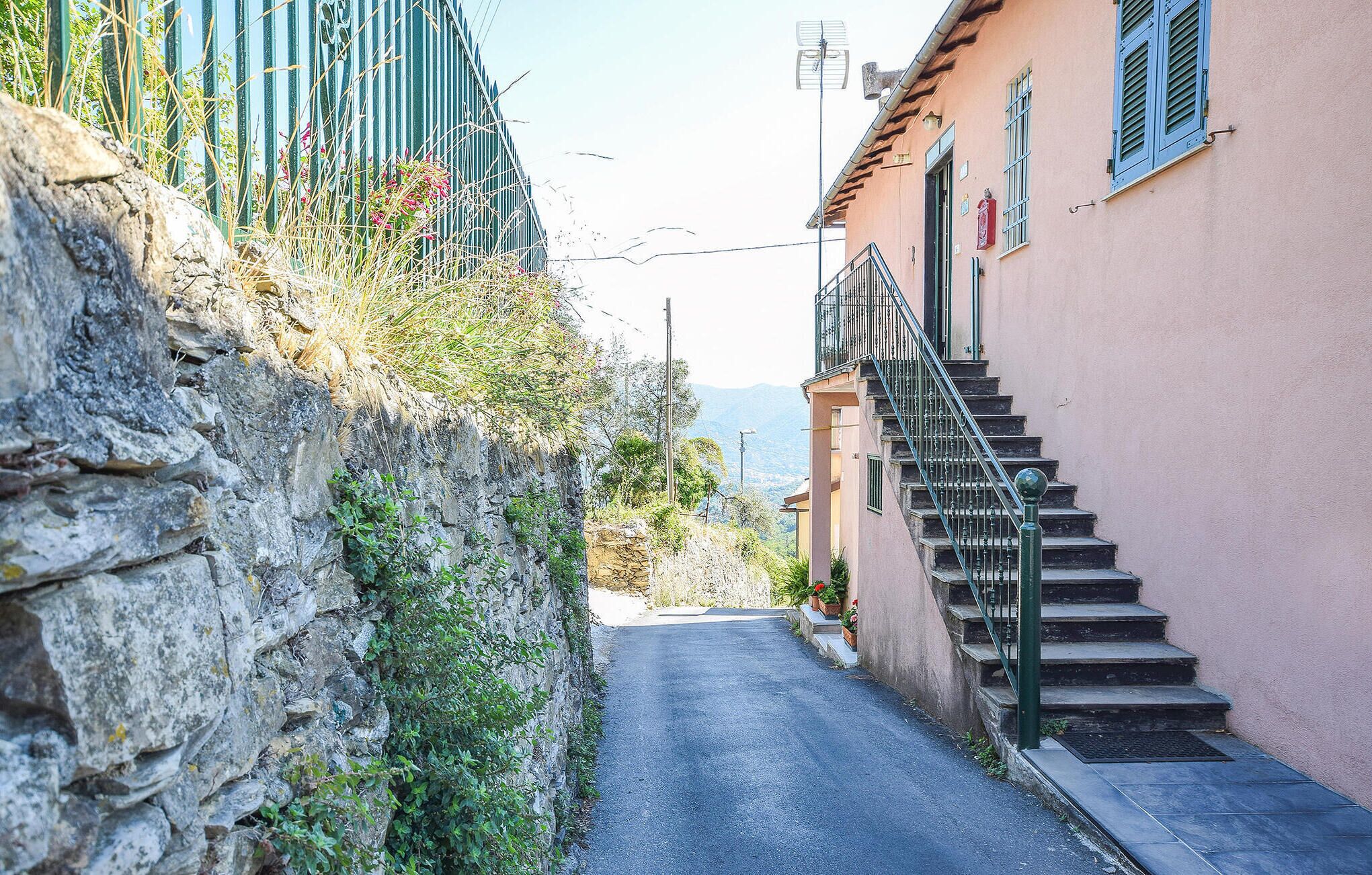 Eine schmale Gasse mit einer Steinmauer an einer Seite und einem Gebäude mit einer Treppe an der anderen.