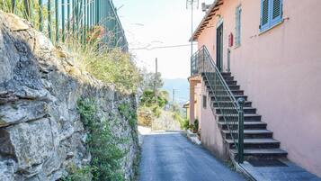 Eine schmale Gasse mit einer Steinmauer an einer Seite und einem Gebäude mit einer Treppe an der anderen.