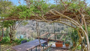 An outdoor patio with a wooden table and chairs, surrounded by greenery and a pergola structure. - Nice apartment in Camogli with WiFi (Camogli)