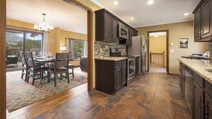 A modern kitchen with dark wood cabinets, a central island, and a view of the outdoors. - Exceptional Views, hot tub -A Mountain Life! #3245 (Estes Park)