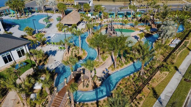 A resort with multiple swimming pools, palm trees, and a winding water slide.