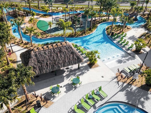 Un resort con una piscina grande, sillones de descanso y una cabaña techada de paja.