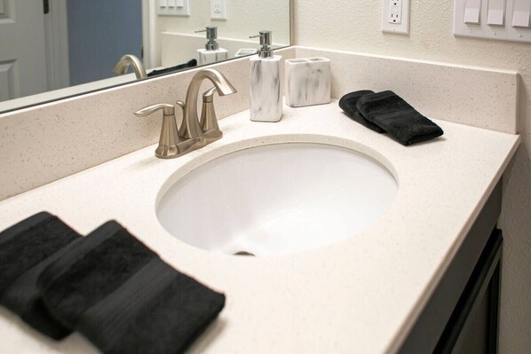 A bathroom with a sink, mirror, and two black towels. - K-Gated Resort-5 miles to Disney-2 FREE Water Park (Osceola County)
