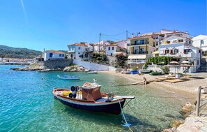 A coastal village with traditional white buildings, a clear blue sea, and a small boat docked near the shore. - Awesome home in Samos (Samos)