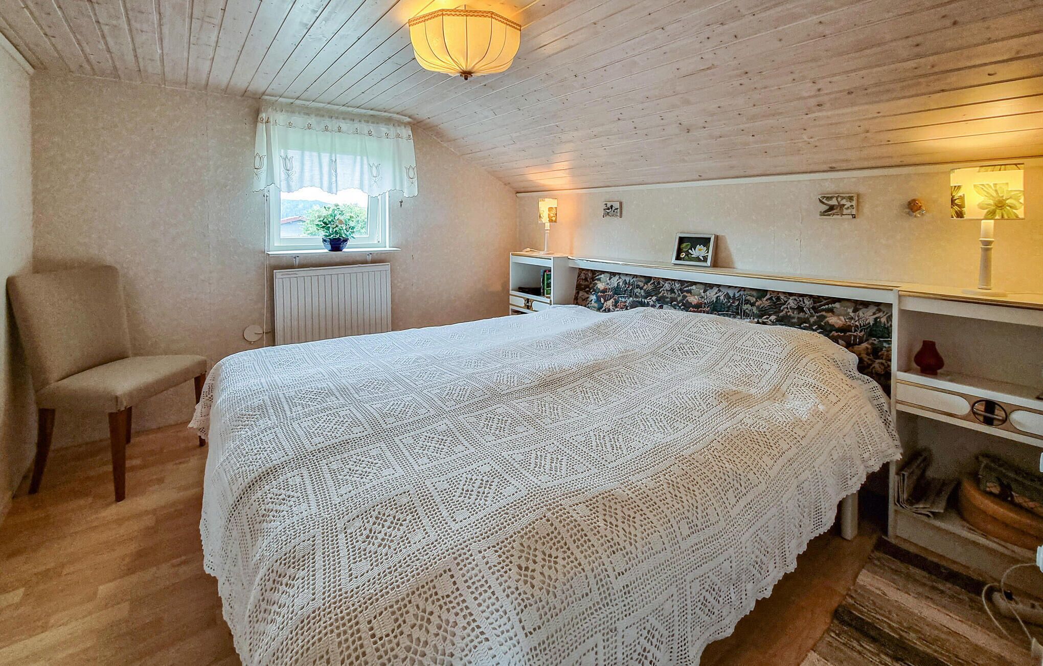 A cozy bedroom with a large bed, a chair, a window with a view, and a radiator.