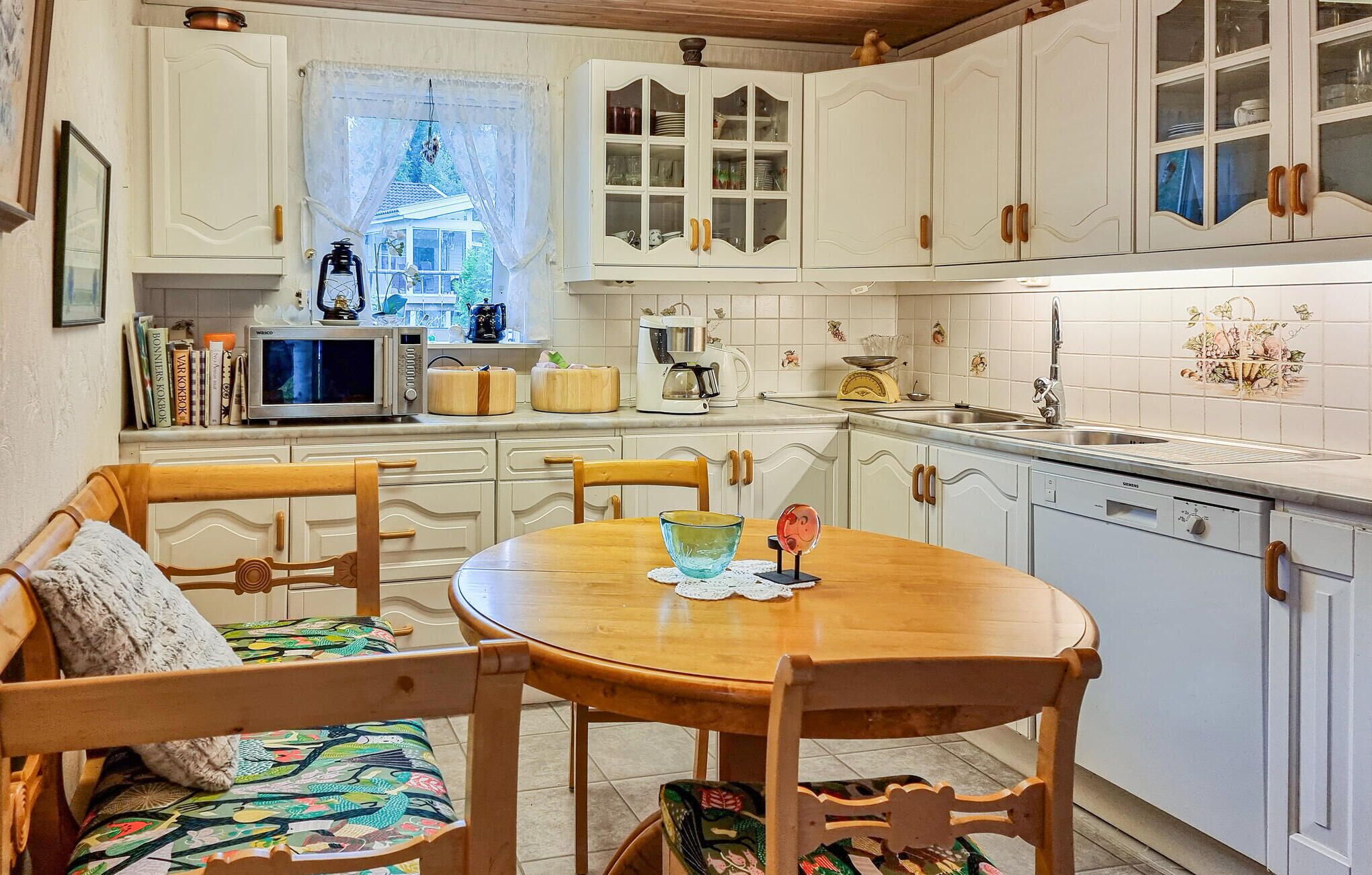 A traditional kitchen with white cabinets, a wooden dining table, and chairs.