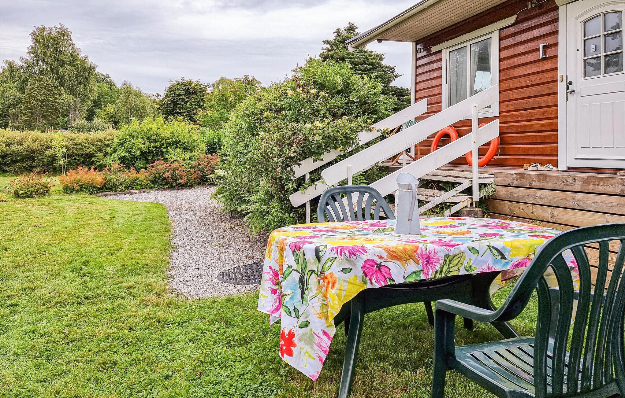 A wooden cabin with a gravel path leading to a table set with a floral tablecloth.