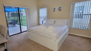 Ein Schlafzimmer mit einem Bett, einem Schreibtisch und einer Schiebetür zu einer Terrasse.