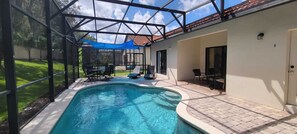 Ein Swimmingpool mit Glasverkleidung, umgeben von einer Terrasse mit Gartenmöbeln.