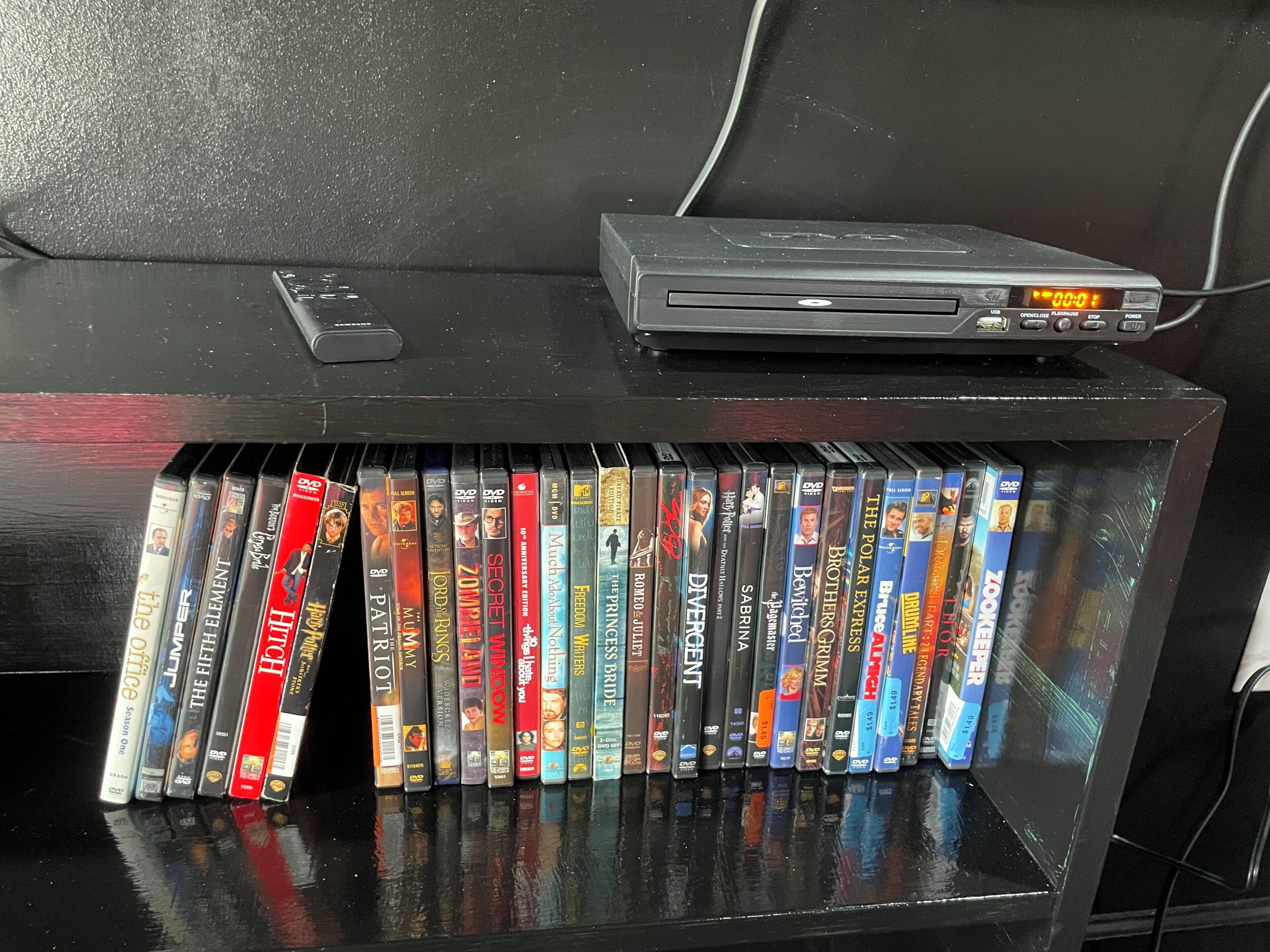 Un estante con una colección de DVDs y un reproductor de DVD.