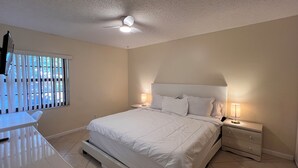 Un dormitorio con cama, mesitas de noche, un escritorio y un ventilador de techo.