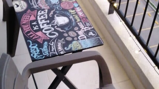 A balcony with a table and chairs, decorated with string lights and a table with coffee-related illustrations. - Amazing Condo with Pool - Magnífico Condo con Piscina (Yumbo)
