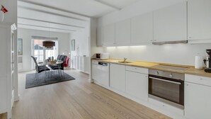 Une cuisine moderne avec des meubles blancs, un plan de travail en bois et un four encastré.