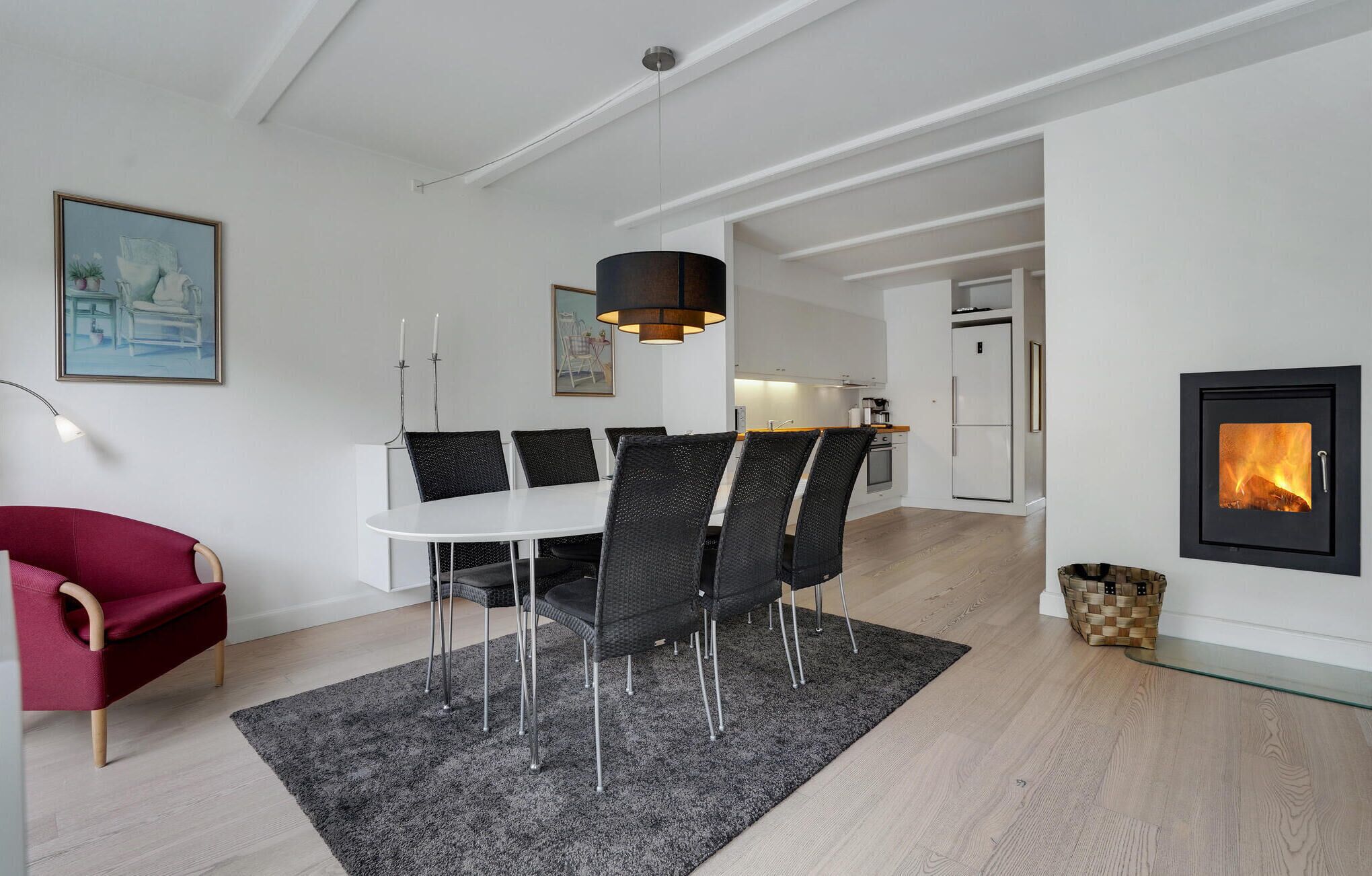 A modern living room with a dining area, a fireplace, and a kitchen.
