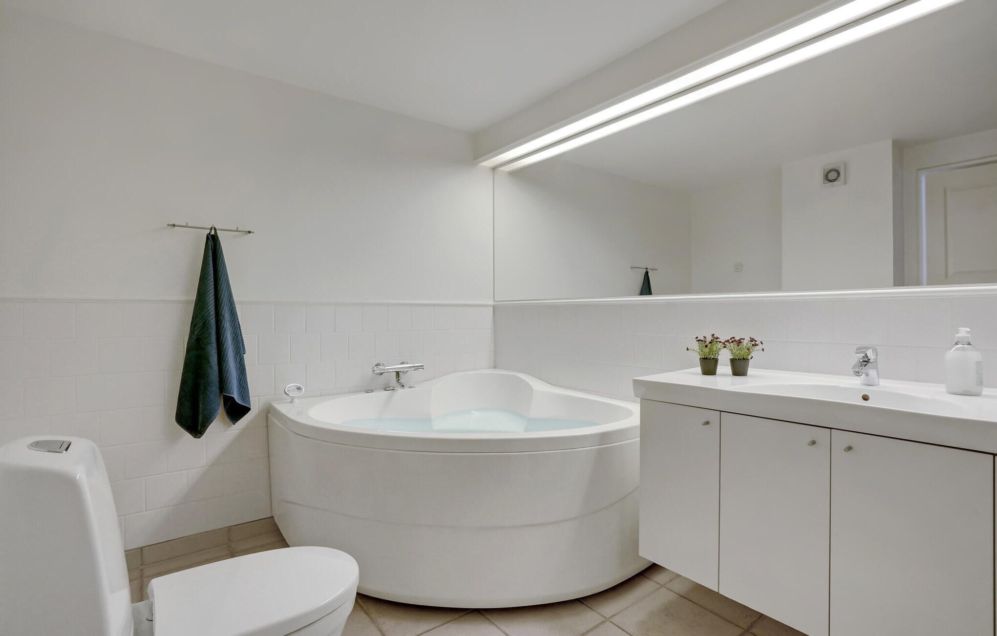 Ein modernes Badezimmer mit einer freistehenden Badewanne, einer Toilette und einem Waschtisch mit Spiegel.