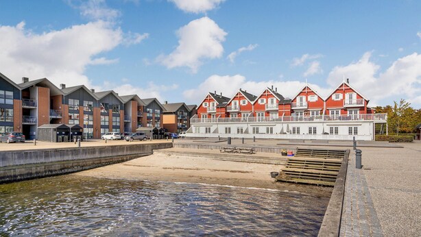 Un hôtel situé au bord de l’eau, doté d’une architecture moderne, d’une plage de sable et offrant une vue dégagée sur l’eau.