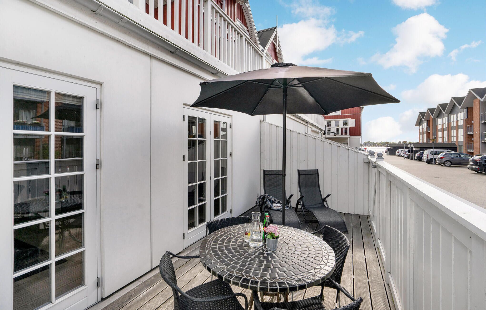 Un balcon avec une table ronde, des chaises et un grand parasol.