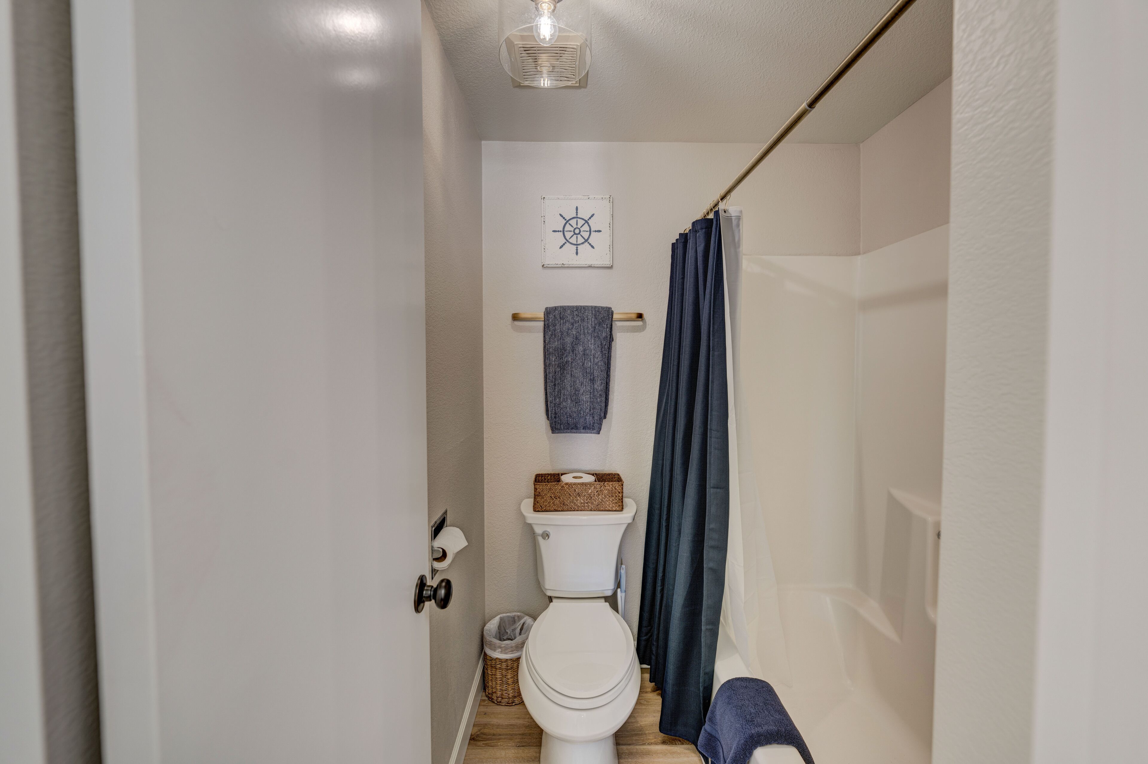 Een kleine, praktische badkamer met een toilet, een handdoekhouder en een douchegordijn.