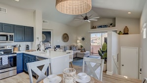 Una cocina moderna con armarios azul oscuro, una isla blanca y una zona de comedor con mesa y sillas de madera.