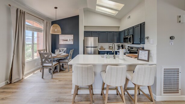 Una cocina moderna con una isla central, armarios oscuros y un ventanal grande.