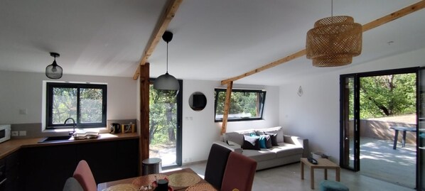 A modern interior with a kitchen, dining area, and living space, featuring large windows and a wooden ceiling. - Cozy house, nature & tranquility, near shopping (Champtercier)